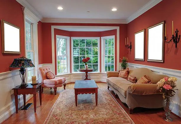 View of a traditional living room with a bay window in the background. Horizontal format.