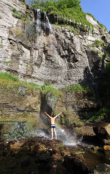 Cтоковое фото Молодой человек под водопадом с rainbow