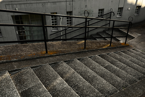 Rusting metal handrail on an old set of stairs, wet from rain.