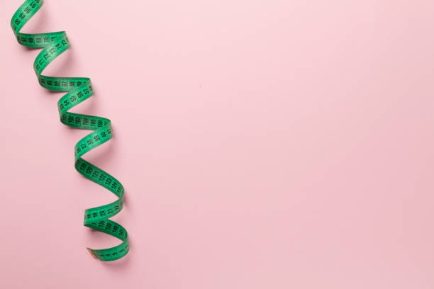 istock Green measuring tape on color background, top view 1470046711