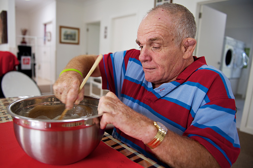 Senior man with an intellectual disability doing some meal preparation.  This image can be used to show the value of meaningful activity in contributing to the quality of life of people with a disability.