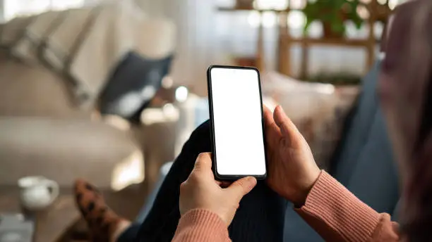 Photo of Woman using phone with white screen while lying on sofa at home , mock up screen