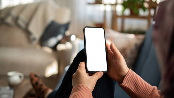 kobieta korzystająca z telefonu z białym ekranem leżąc na kanapie w domu, makieta ekranu - telephone mobile phone human hand smart phone zdjęcia i obrazy z banku zdjęć