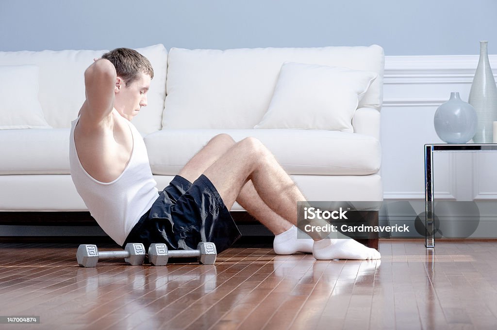 Homem fazendo abdominais na sala de estar - Foto de stock de 20 Anos royalty-free