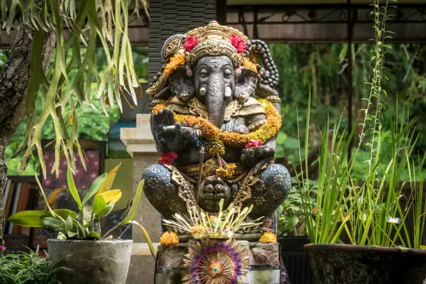 Ganesh Statue decorated with floweers in a temple in Ubud, Bali, Indonesia. Spiritual culture concept