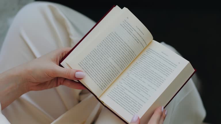 The girl opens and reads a book. The book is on the girl's lap