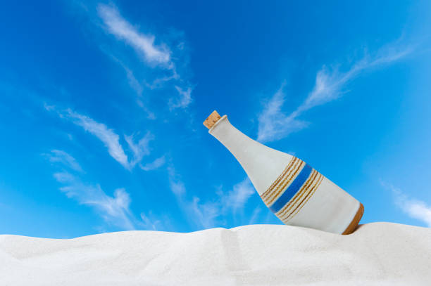Bottle in the sand on sky background