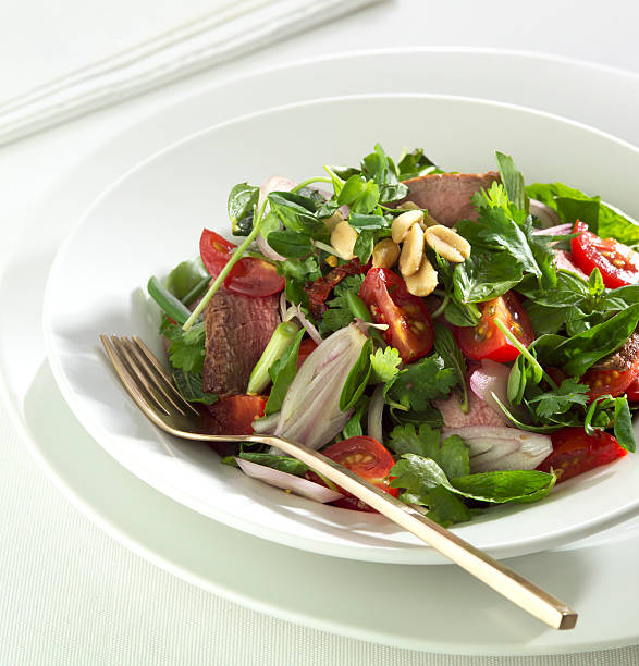 Thai beef salad in a white bowl stock photo
