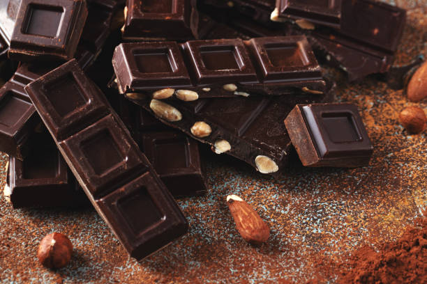 istock Dark and milk chocolate with nuts on a dark background sprinkled with cocoa powder. 1470059052