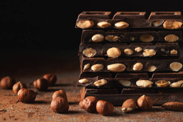 istock Dark and milk chocolate with nuts on a dark background sprinkled with cocoa powder. 1470059058