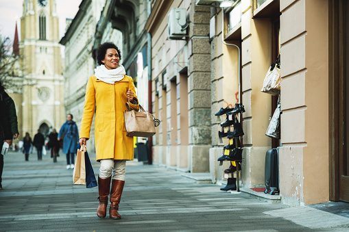 Happy black woman walking on the street with shopping bag.