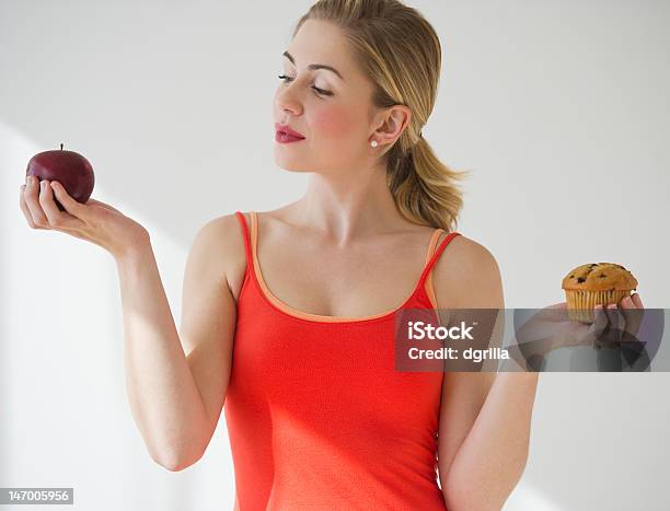 A Woman Holding An Apple In One Hand And A Muffin In Other Stock Photo - Download Image Now