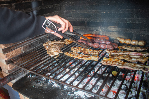 chef cooking grilled meat over the fire in a homemade barbecue