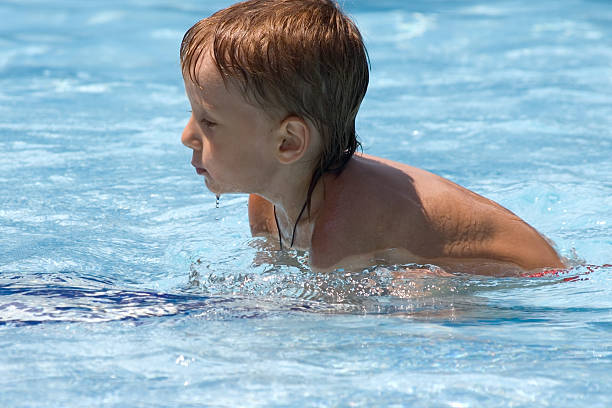 istock boy tries to swim in a pool 147006454