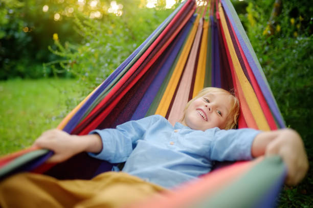 istock Cute little blond white boy enjoy and having fun with multicolored hammock in backyard or outdoor playground. Summer outdoors active leisure for kids. Child relaxing and swinging in hammock. 1470065048