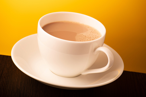 Cup of milk tea on yellow background, indian chai
