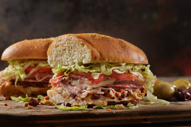 muffuletta, panino italiano con oliva, peperoni arrostiti e carciofi spalmabili - panino submarine foto e immagini stock