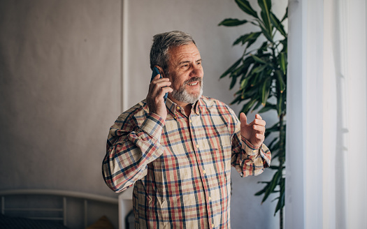 An elderly man is talking using a mobile phone