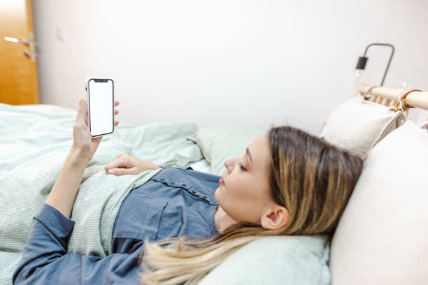 istock Young woman is waking up and holding smart phone with white screen 1470066581