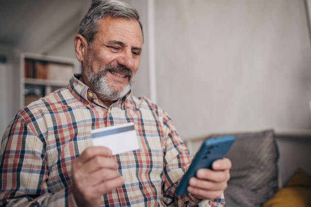 istock Senior man with beard shopping online from home, using smart phone 1470067982