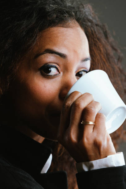istock Elegantly dressed black woman drinking coffee, amused expression 1470070902