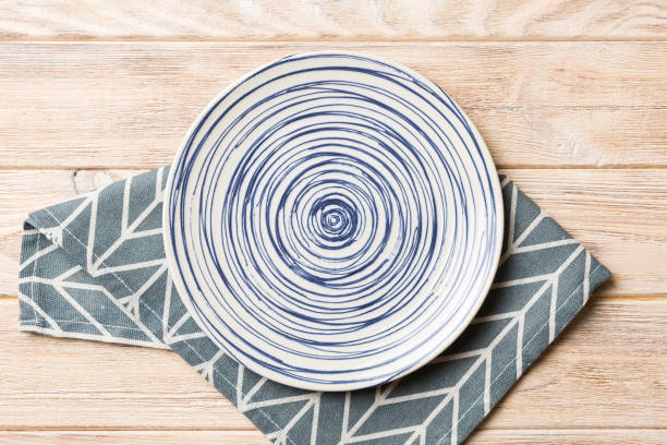 istock Top view on colored background empty round blue plate on tablecloth for food. Empty dish on napkin with space for your design 1470075128