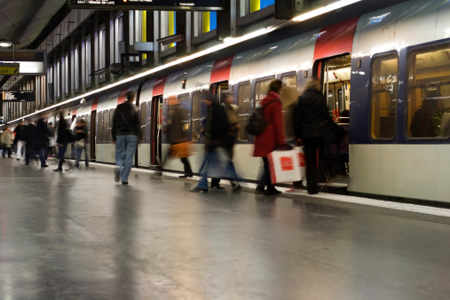 Busy weekend commuters board an RER train. The Paris RER trains link to the city's metro network. Note that two advertisements and one woman's face have been removed. Long shutter speed implies motion and activity.