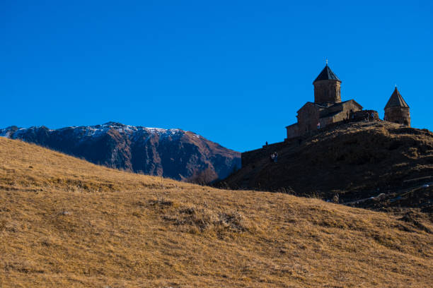 istock amazing panorama of ancient Gergeti Trinity Church and glorious Caucasus mountains, Panoramic landscape of beautiful natural mountains  peaks and meadow, Kazbegi, Georgia 1470079335