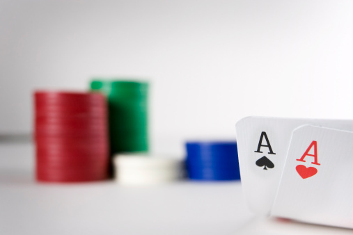 A pair of poker aces are carefully revealed to the player in front of his piles of chips