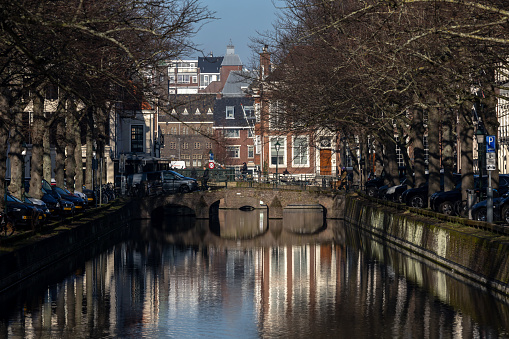 The Hague, Netherlands, Feb 7, 2023 A view of a small canal in the downtown on Smidswater and a cyclist on a bridge.