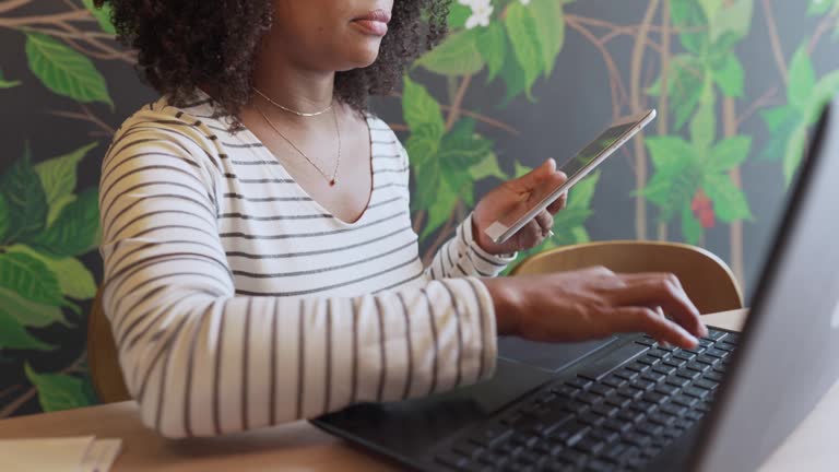 Young woman working on a laptop and tablet over coffee in a cafe