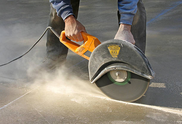 Man cutting control groove in concrete slab stock photo