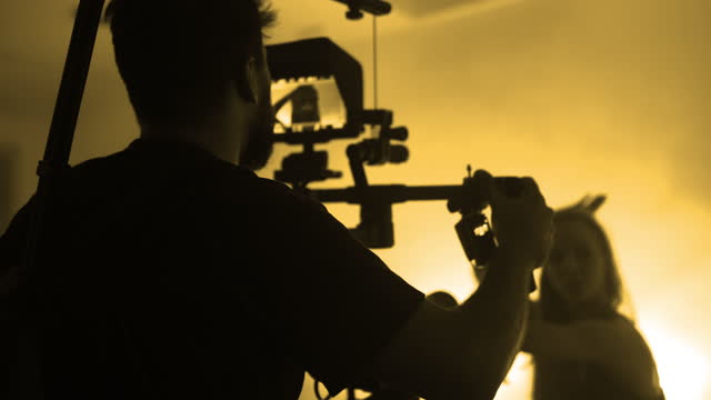 Camera operator moving Red Helium with gimbal stabilized device on professional production film set with modern dancers performing contemporary dance