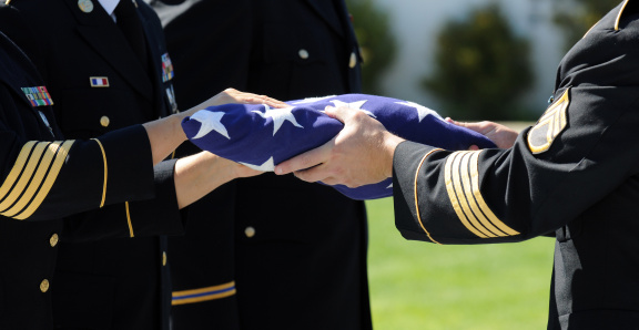 Officers Of A Military Honor Guard carefully prepare a flag that graced the casket of one of America's fallen heros.
