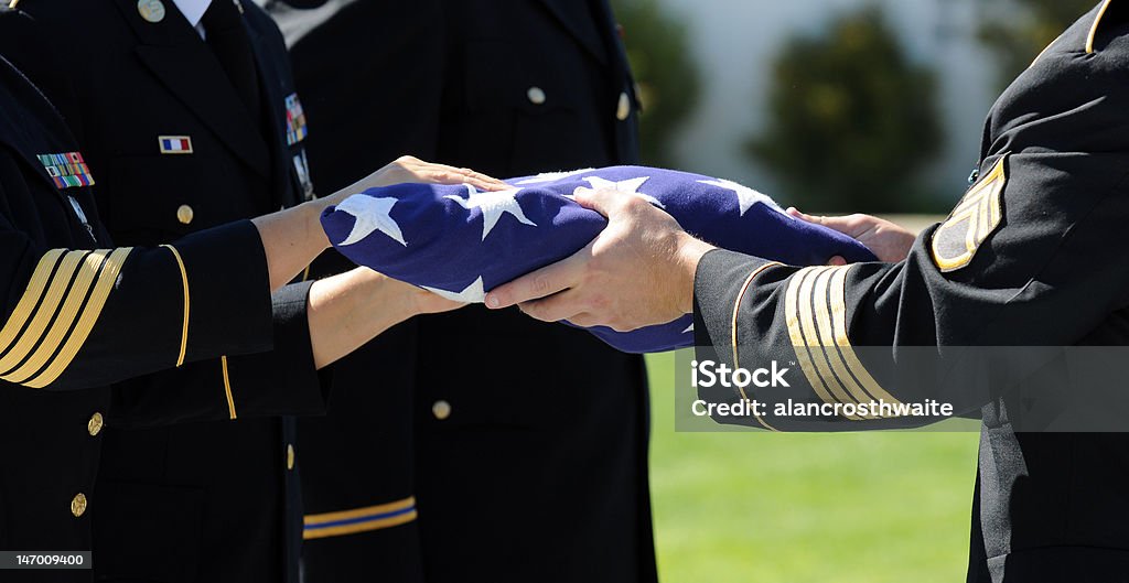 Honoring A Fallen Hero Officers Of A Military Honor Guard carefully prepare a flag that graced the casket of one of America's fallen heros. Veteran Stock Photo