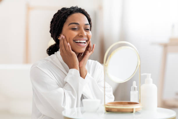 istock Self-Care Concept. Beautiful Black Woman Looking At Magnifying Mirror And Touching Face 1470095435