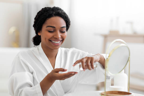 istock Smiling Black Female Using Cotton Pad And Micellar Water For Skincare Routine 1470095600