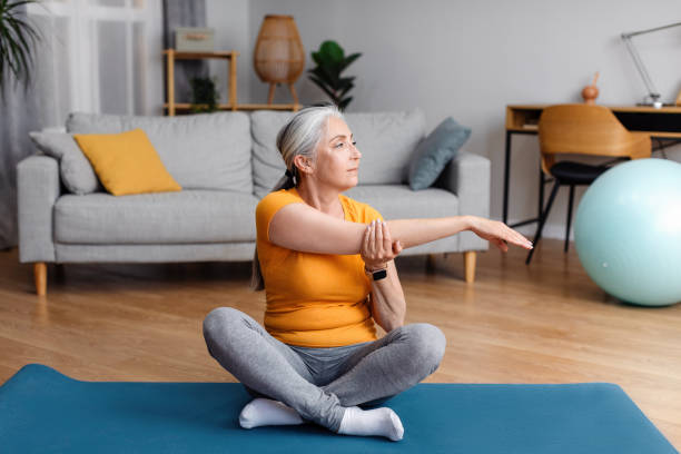 istock Active senior woman stretching her arm on mat at home, doing flexibility exercises, practicing yoga or pilates 1470095662
