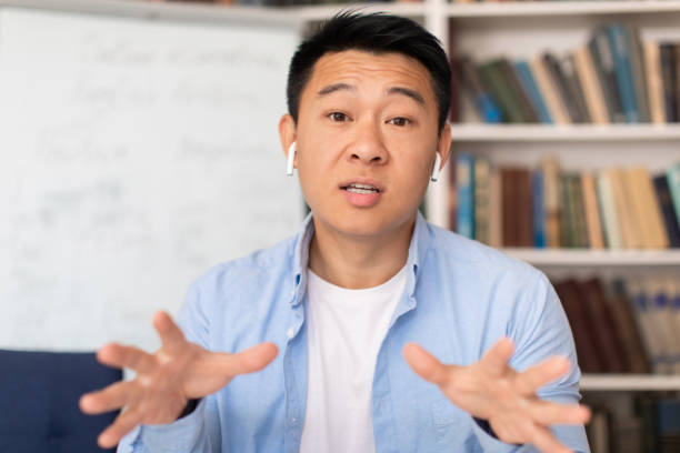 istock Korean Teacher Video Calling Talking To Camera In Modern Library 1470095700