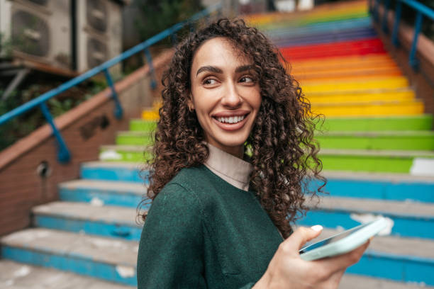 joven atractiva mujer se para cerca de las escaleras del arco iris en estambul y usando un teléfono - staircase steps istanbul turkey fotografías e imágenes de stock