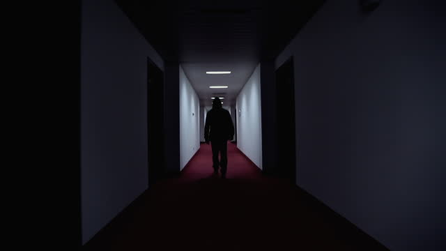 Man walking in a creepy hotel corridor