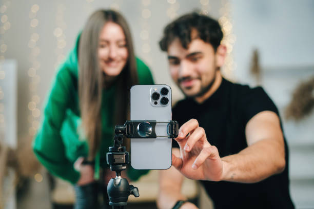 Couple using smartphone turning on music enjoying dance together performing and recording video blogging. Lifestyle bloggers creating entertainment content for their vlog