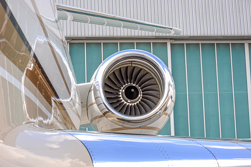 Right side engine of a small business jet. The engine is in focus with a clear blue sky in the background and the fuselage in soft focus in the foreground.