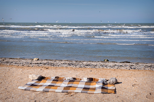Plaid in a cage lies on the beach near the sea. Rest, relaxation, enjoyment. High quality photo