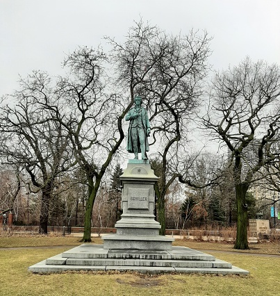 Johann Christoph Friedrich von Schiller Monument by\nErnst Bilhauer Rau in 1886. Located in the \nLincoln Park Conservatory Garden. \n\nFront view of the Schiller Monument framed by bare trees. Picture taken on a cold morning in Chicago February 2023.