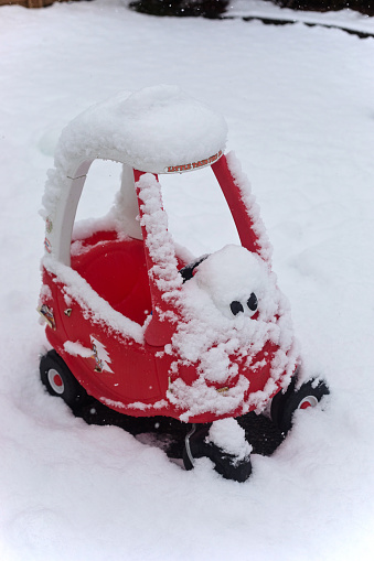 Chemainus, Canada - February 27, 2023. Toddler Little Tikes car gets buried in snow in a backyard.