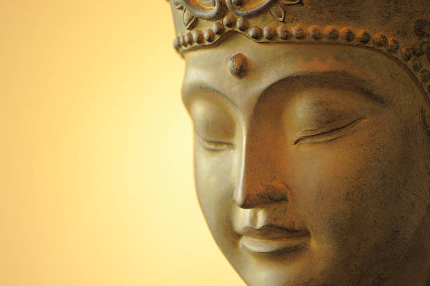 The face of a statue of Buddha on a yellow background stock photo