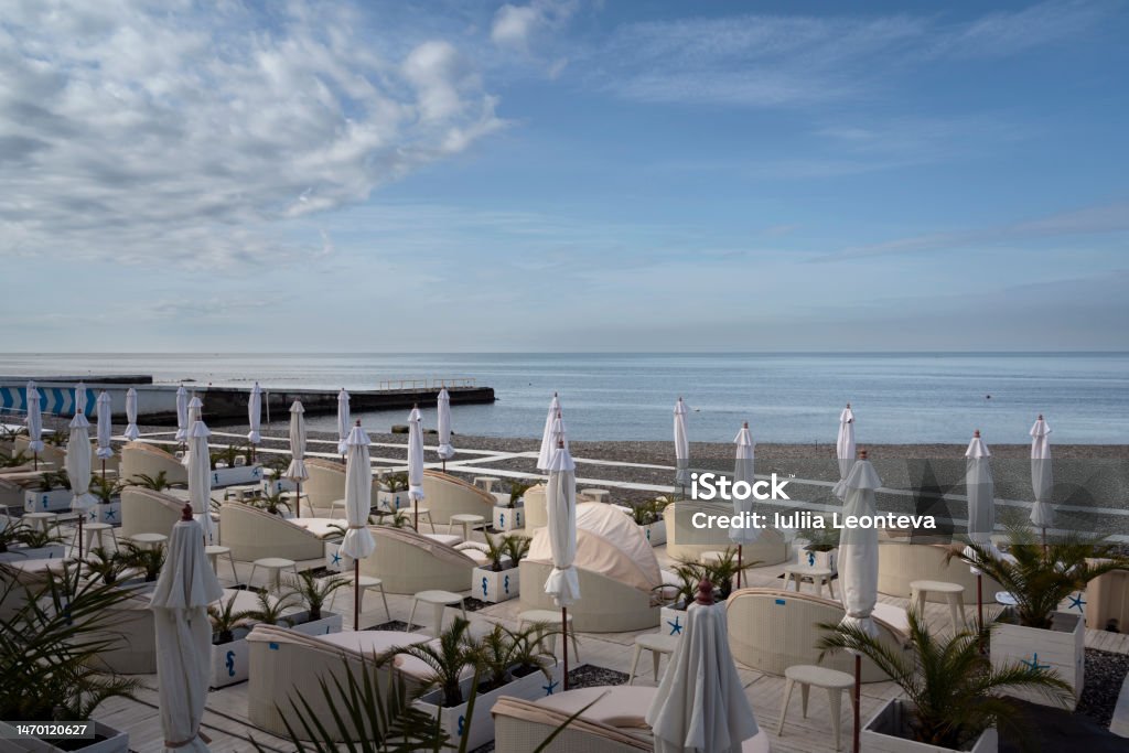 A deserted beach on the coast of Sochi with sun beds and umbrellas against the background of the calm Black Sea, Adler, Krasnodar Territory, Russia Adler District Stock Photo