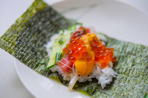 prepara sushi arrotolato a mano con frutti di mare. - temaki food sushi salmon foto e immagini stock