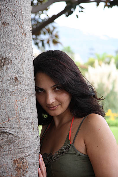 istock young woman leaning at tree flirting 147013060